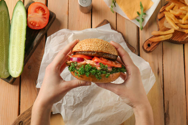 istock Woman eating tasty burger at table 1351065904