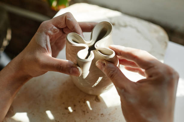 Artist Shaping Pottery Close Up Close up of female hands shaping ceramic bowl in sunlight, copy space clay sculpture stock pictures, royalty-free photos & images