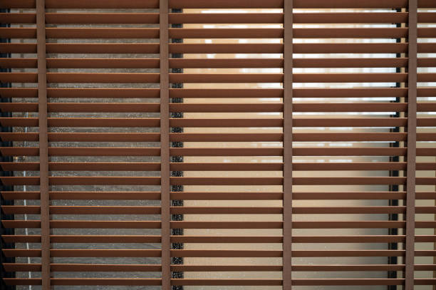 istock Pattern of brown wooden blinds on glass window 1351067164