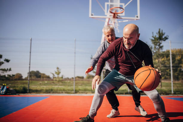 Men playing basketball Two men, senior men playing basketball one on one outdoors. defending sport stock pictures, royalty-free photos & images