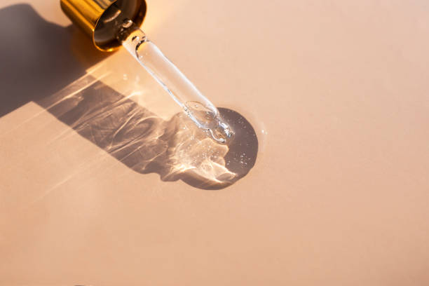 A clear gel-like liquid and a glass pipette casts a shadow on a beige background. Top view, place for text. A clear gel-like liquid and a glass pipette casts a shadow on a beige background. Top view, place for text. acid stock pictures, royalty-free photos & images