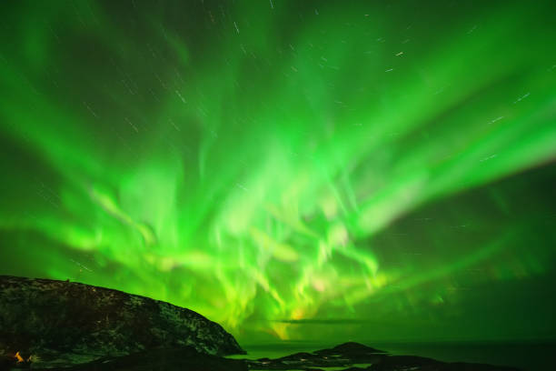istock Aurora Borealis in the night sky over mountains silhouettes. Long exposure, multi colored lights 1351071332