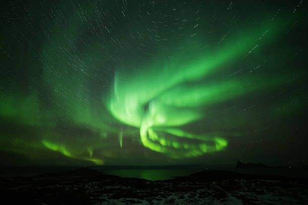 istock Aurora Borealis in the night sky over mountains silhouettes. Long exposure, multi colored lights 1351071346