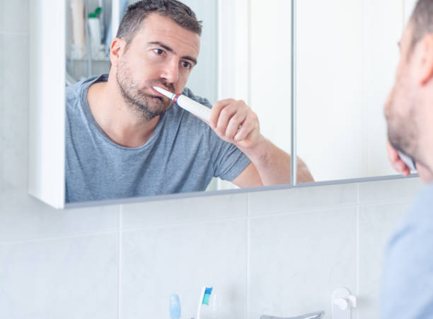 istock Man cleaning teeth using an electric toothbrush 1351071634