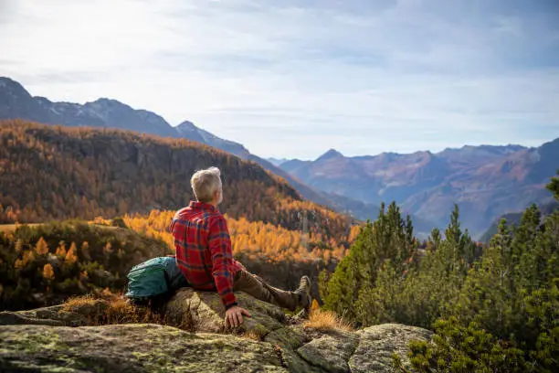 Sitting hiker resting on the mountain peak, autumn mountain valley