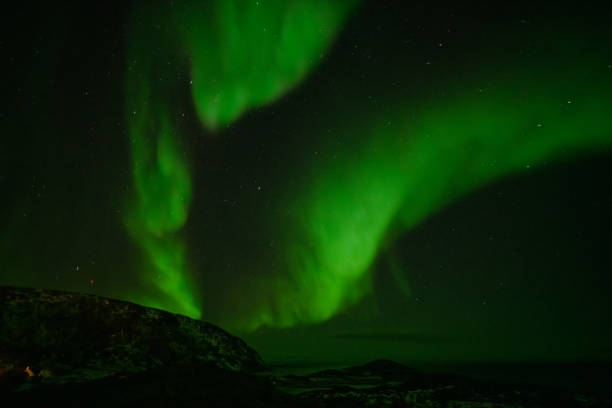 istock Aurora Borealis in the night sky over mountains silhouettes 1351072602