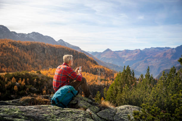 istock Hiker sitting on mountain peak checking smartphone 1351072619