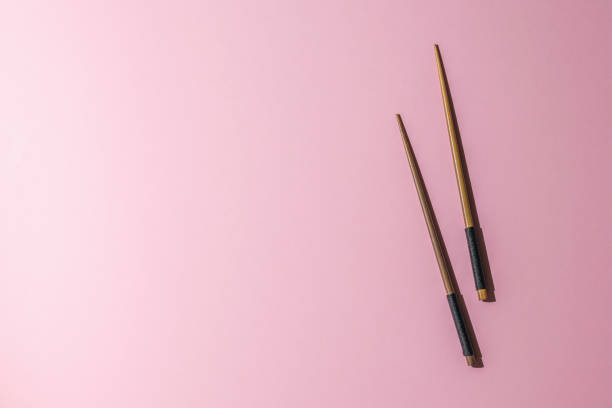 istock Wooden chopsticks on a pink background in bright light. 1351072632