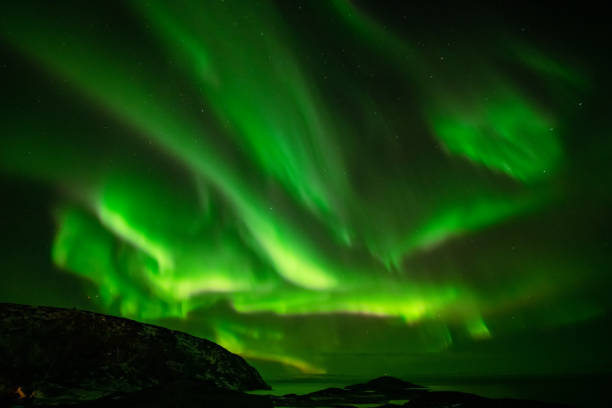 istock Aurora Borealis in the night sky over mountains silhouettes 1351072681