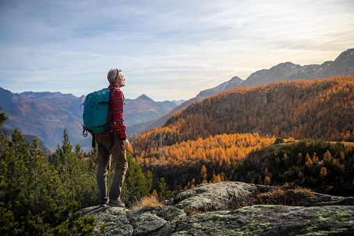 Mature man standing in front of the mountain valley in autumn