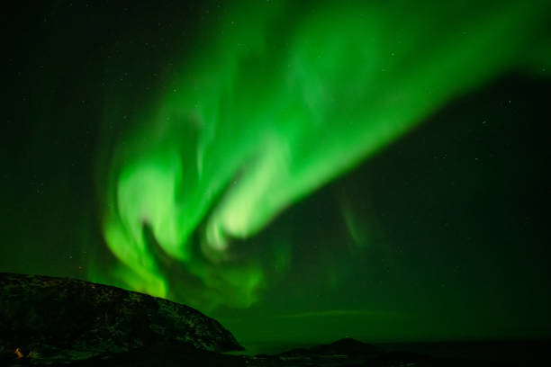 istock Aurora Borealis in the night sky over mountains silhouettes 1351072730