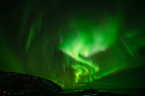 istock Aurora Borealis in the night sky over mountains silhouettes 1351072731