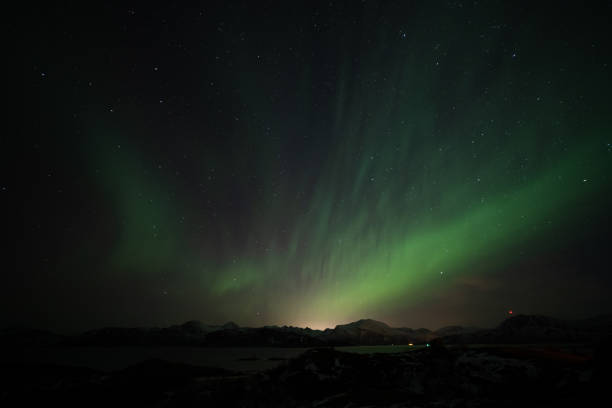 istock Aurora Borealis in the night sky over mountains silhouettes. Long exposure, multi colored lights 1351072793