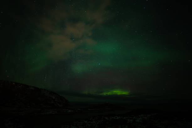 istock Aurora Borealis in the night sky over mountains silhouettes 1351072835