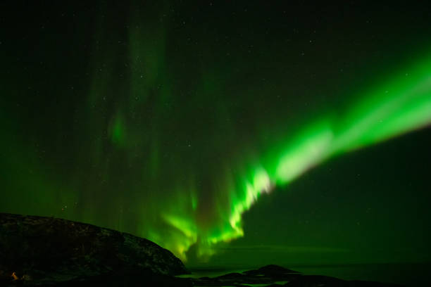 istock Aurora Borealis in the night sky over mountains silhouettes 1351072866