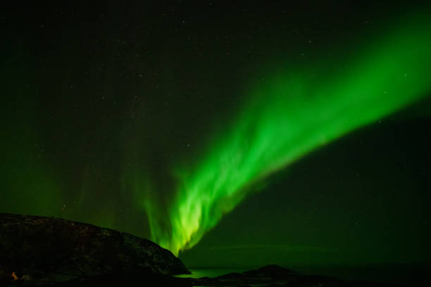 istock Aurora Borealis in the night sky over mountains silhouettes 1351072867