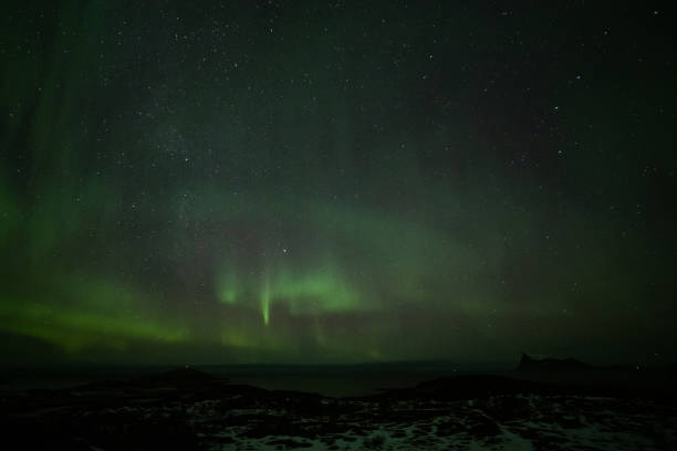 istock Aurora Borealis in the night sky over mountains silhouettes. Long exposure, multi colored lights 1351072872