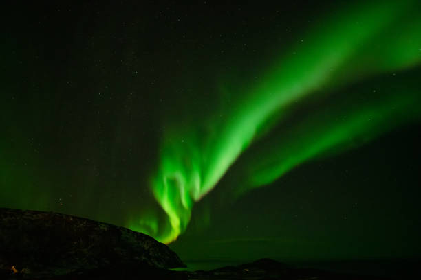 istock Aurora Borealis in the night sky over mountains silhouettes 1351072887
