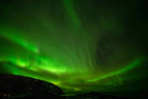 istock Aurora Borealis in the night sky over mountains silhouettes 1351072895