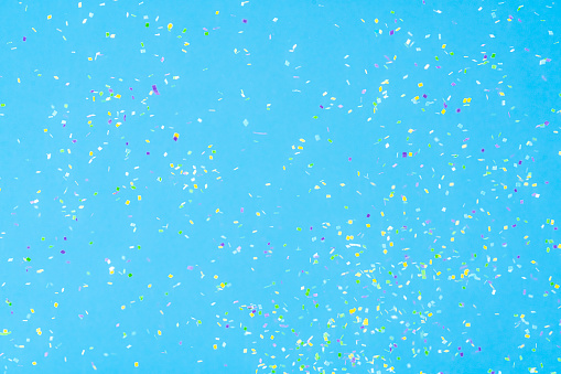 Birthday, party, celebration, New Year or Christmas celebration concept. Multi colored confetti falling against pastel colored blue background. High resolution 42Mp studio digital capture taken with Sony A7rII and Sony FE 90mm f2.8 macro G OSS lens