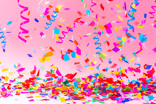 Birthday, party, celebration, New Year or Christmas celebration concept. Multicolored confetti and streamers falling against pastel colored pink background. High resolution 42Mp studio digital capture taken with Sony A7rII and Sony FE 90mm f2.8 macro G OSS lens