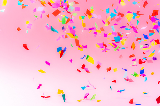 Birthday, party, celebration, New Year or Christmas celebration concept. Multicolored confetti falling against pastel colored pink background. High resolution 42Mp studio digital capture taken with Sony A7rII and Sony FE 90mm f2.8 macro G OSS lens