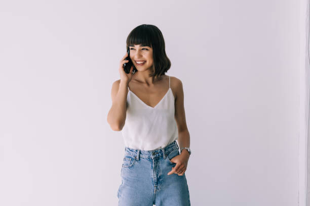 istock Young woman talking on mobile phone against white background 1351075964