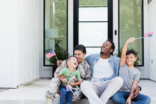 istock Diverse military family sits on front steps and waves flags 1351076137