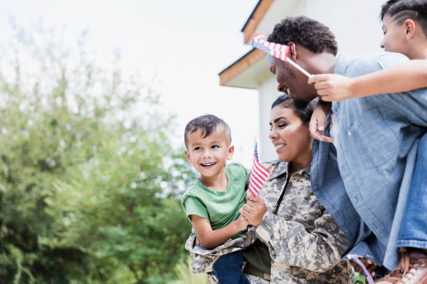istock Female soldier and husband carry sons and wave flags 1351076140