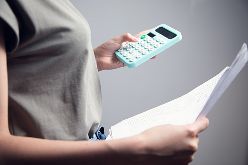 Business woman counting on calculator and holding documents in hands