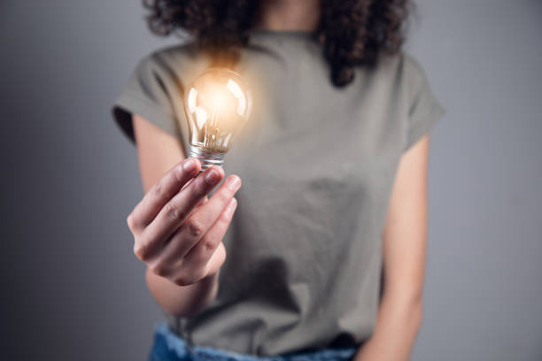 istock young woman holding light bulb 1351077719