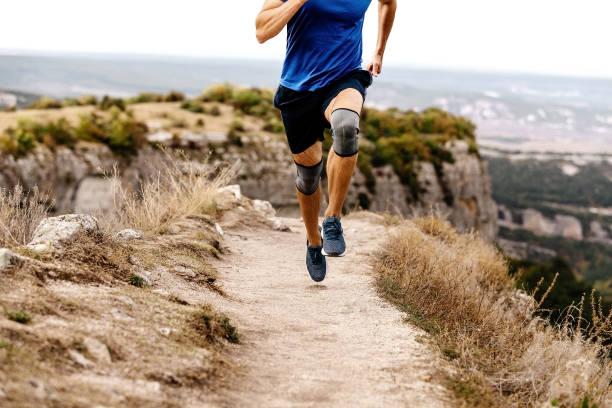 male runner run mountain trail with knee pads male runner run mountain trail with knee pads kneepad stock pictures, royalty-free photos & images