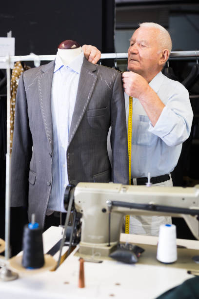 istock Mature male tailor takes measurement from his jacket using measuring tape 1351085824