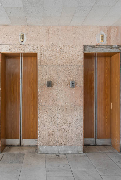 istock Closed old Soviet wooden elevator doors in the old interior in the style of modernism, with walls lined with travertine. 1351085924