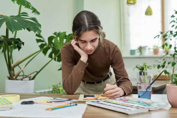 Teenager guy artist painting with watercolors at home stock photo
