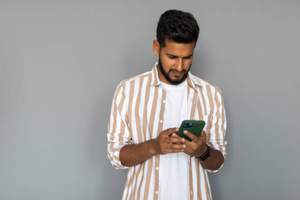 istock Portrait of indian young man using phone on white background 1351087170