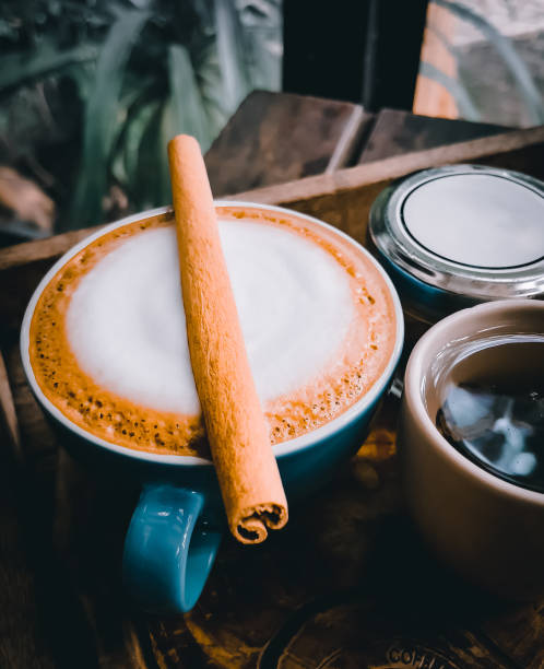 Blue coffee cup and cinnamon sticks on wood table in the garden