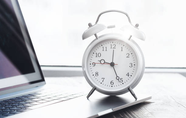 istock Work time concept. Home desktop with laptop and alarm clock on desk 1351089202