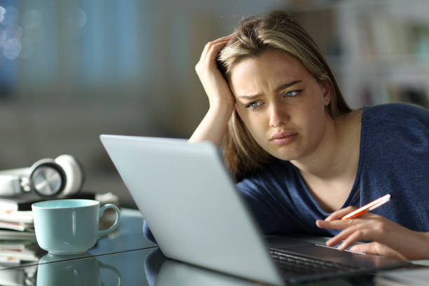 Frustrated student e-learning in the night at home stock photo