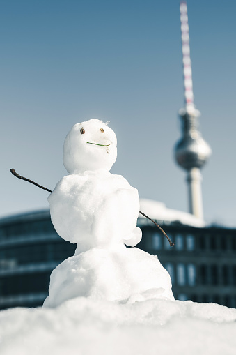little snowman in front of Berlin cityscape with tv-tower in the winter sun