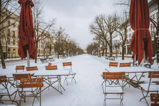 snow capped chairs and tables of empty street cafe on snowy Berlin boulevard Unter den Linden