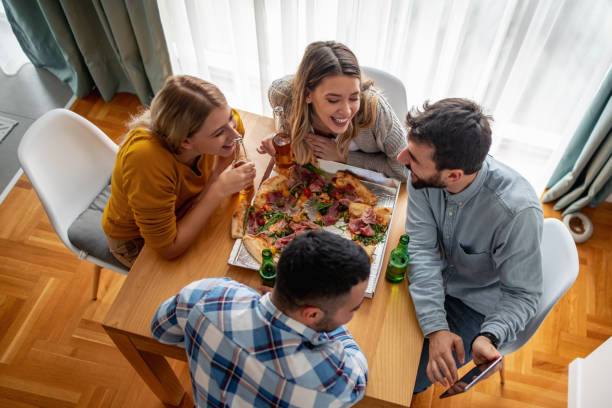 Friends eating pizza at home party stock photo