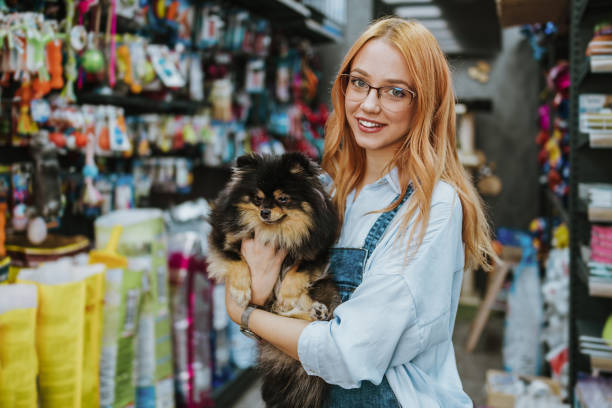 Woman in pet shop Young adult redhead woman enjoying in visit and shopping in petshop store together with her adorable Chihuahua dog. pet equipment stock pictures, royalty-free photos & images