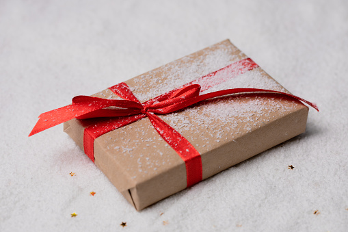 New Year's gift on the snow with a red ribbon. Stock photo