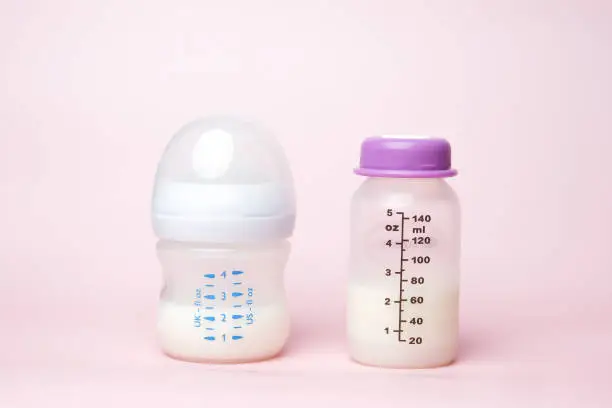 A picture of drink and storage baby bottle on pink background.