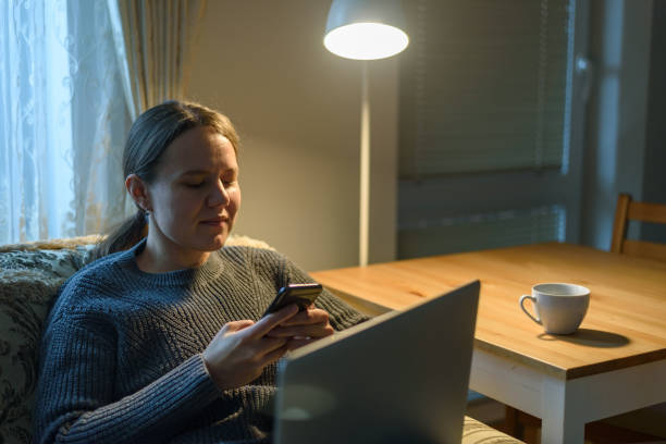 istock Woman using her phone sitting near laptop 1351098592