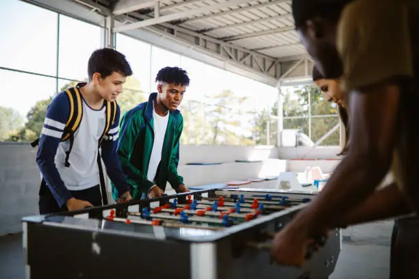 High school kids playing table soccer after classes in the school yard.