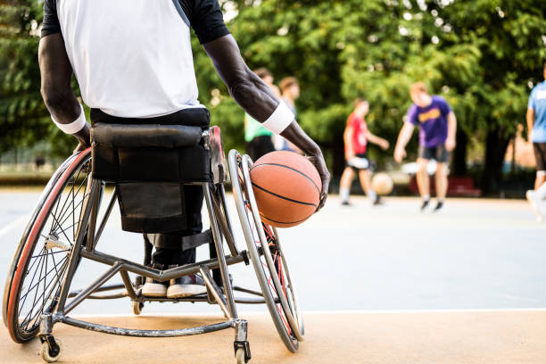 giocatore di basket afroamericano in carrozzina in attesa di giocare su campo all'aperto, concetto di accessibilità allo sport per atleta disabile, inclusione sociale - basket su sedia a rotelle foto e immagini stock