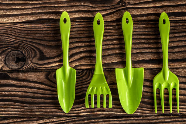 istock Gardening tools concept. Spade, rake and fork on wooden background with space for text flat lay top view. 1351105878