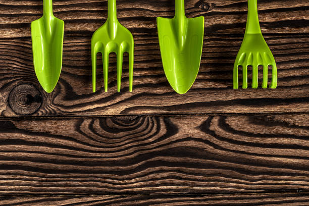 istock Gardening tools concept. Spade, rake and fork on wooden background with space for text flat lay top view. 1351105916